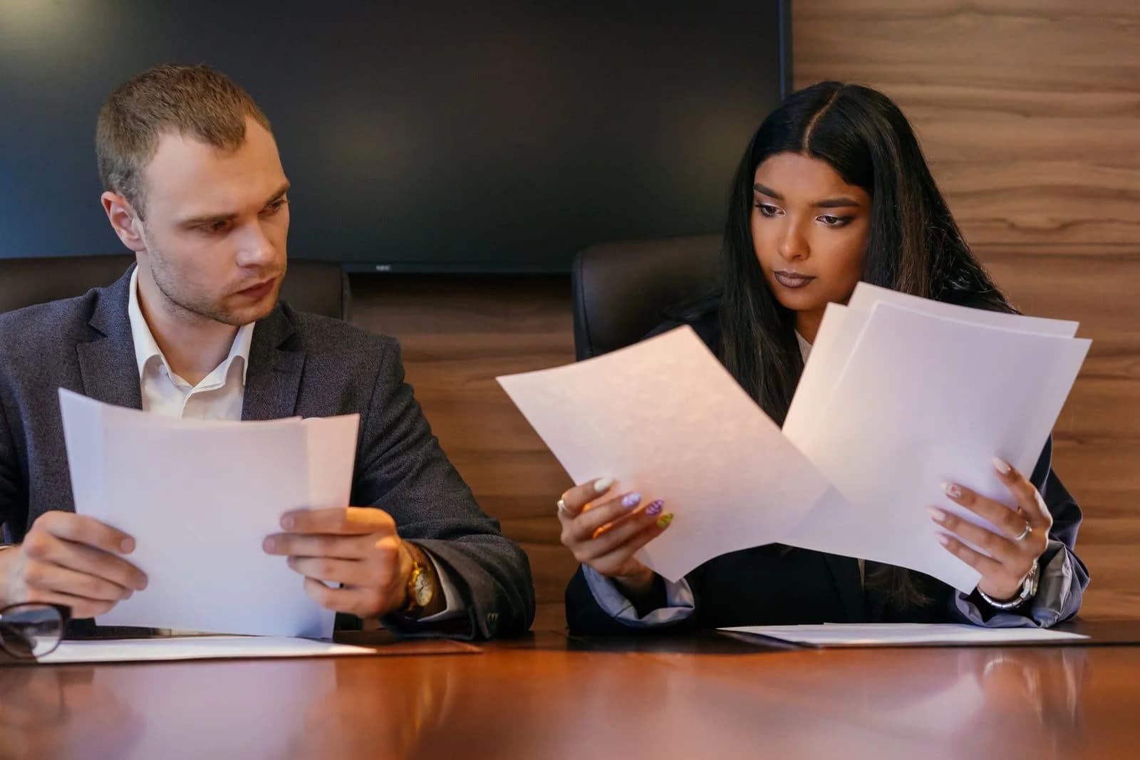 Two office professionals reviewing a set of documents.