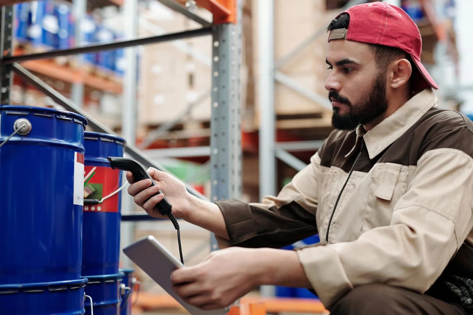 A warehouse worker checking inventory with a scanner and tablet.