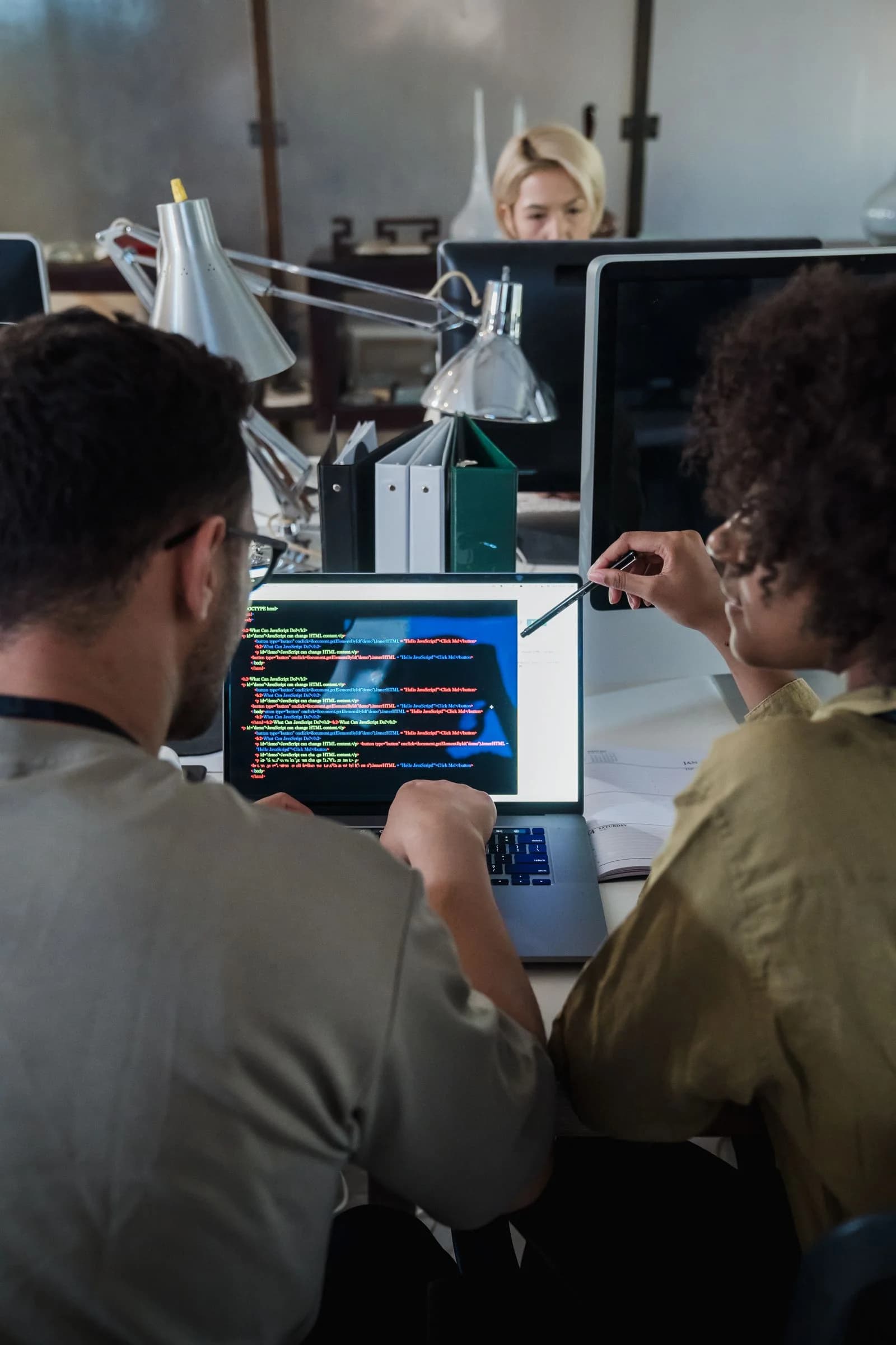 Two colleagues discussing software on a laptop in an office.