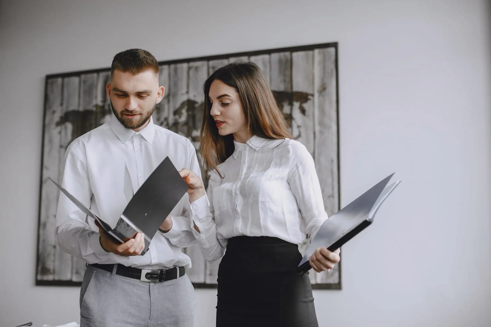 Two colleagues comparing documents during an office review.